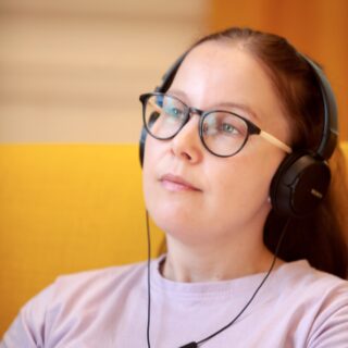 Nainen kuuntelee kuulokkeilla