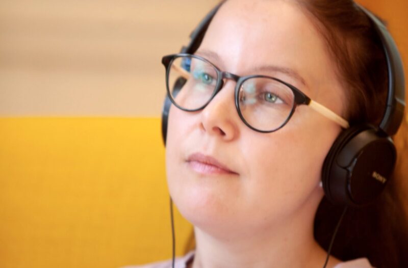 Nainen kuuntelee kuulokkeilla